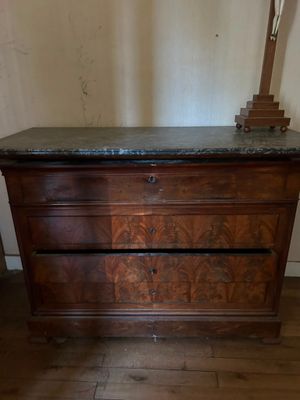 une commode en bois avec un plateau en marbre et une lampe posée dessus