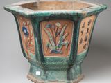 a green vase with a design on the outside of it