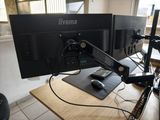 deux écrans posés sur un bureau, avec un clavier et une souris