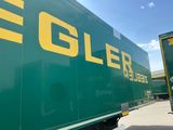 un grand camion vert avec un lettrage jaune sur le côté