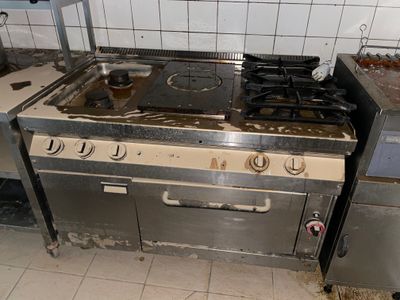 a dirty kitchen with a stove and oven in it