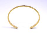 a close up of a gold cuff bracelet on a white background