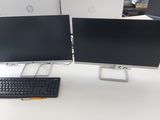two computer monitors and a keyboard on a desk