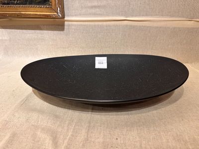 une assiette noire posée sur une table, avec une photo en arrière-plan