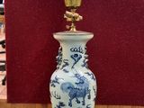 un vase bleu et blanc sur lequel est posée une lampe dorée