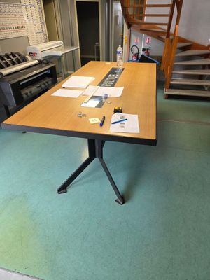 une table recouverte de papiers, au milieu d'une pièce
