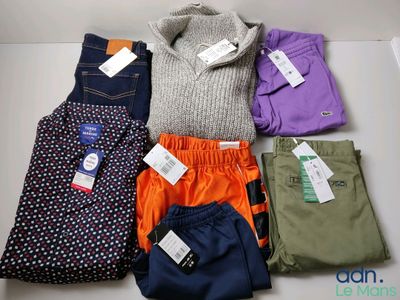 Plusieurs paires de pantalons et de pulls sont disposés sur une table
