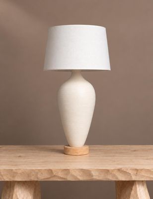 une lampe de table blanche posée sur une table en bois, près d'un mur marron