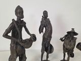 three bronze figurines of a man and a woman with a cow