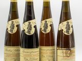 four bottles of wine are lined up on a white surface