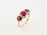 a gold ring with three ruby stones on top