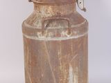 an old milk can is sitting on a white surface
