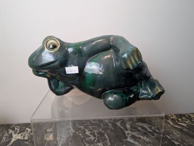 a green frog statue on a clear stand on a marble floor