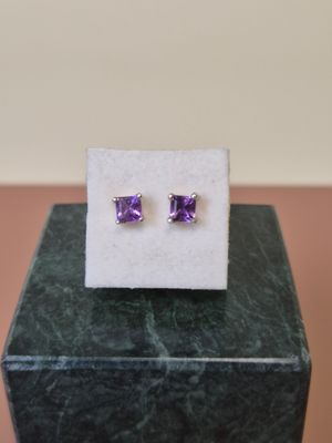 une paire de boucles d'oreilles en amethorate posées sur un bloc de marbre