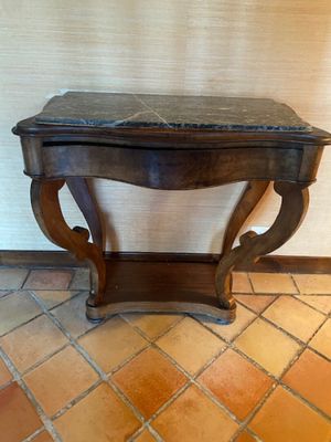 a small wooden table with a marble top on a tiled floor