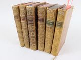 plusieurs vieux livres sont empilés sur une surface blanche