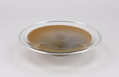 un bol en verre contenant un liquide, posé sur une surface blanche