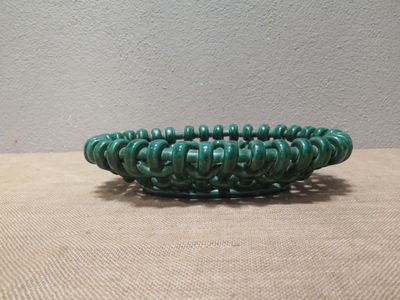 green beaded bowl sitting on a table in front of a wall