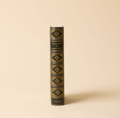 un vieux livre posé sur une table à côté d'un mur blanc