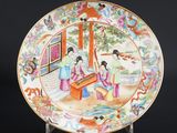 une image représentant une assiette sur laquelle est peinte une femme jouant d'un instrument de musique