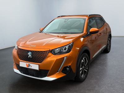 La voiture orange est garée dans une grande pièce au sol noir.