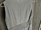 grey sleeveless dress with lace trim on a hanger in front of a curtain