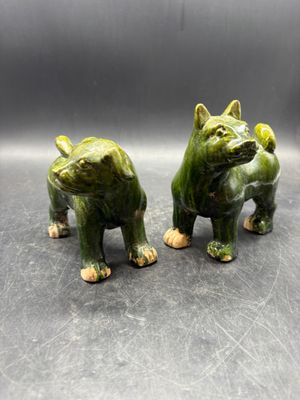 two green ceramic figurines of a dog and a cat on a table