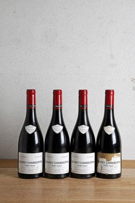 quatre bouteilles de vin rouge alignées sur une table en bois
