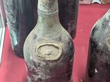 several old bottles are sitting on a red cloth on a table