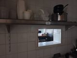une fenêtre dans le mur d'une cuisine, sur laquelle sont posés des casseroles et des poêles