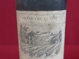 an old bottle of wine sitting on top of a red table