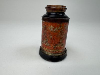 un petit vase avec un couvercle posé sur une surface blanche