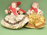 pair of porcelain dolls sitting on a green surface