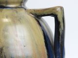 a blue and brown vase with a handle on a table