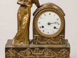 une horloge en or, avec une femme debout à côté