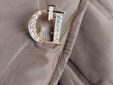 une broche en or sur laquelle figure la lettre « d »