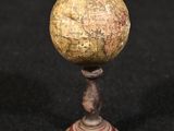 un vieux globe posé sur un socle en bois, sur une surface noire