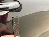 a person holding a ruler to measure a car ' s body