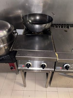 une plaque de cuisson en acier inoxydable sur laquelle sont posées deux casseroles, dans une cuisine professionnelle