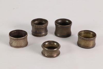 six antique brass napkin holders on a white surface