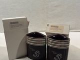 two black coffee cups sitting next to a white box on a table