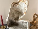 a statue of a man sitting on a table next to a candle