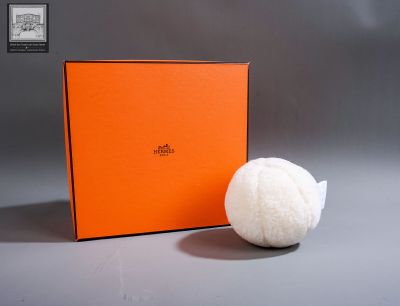 une boîte orange à côté de laquelle se trouve une balle blanche, posée sur une table