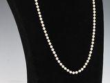 a white pearl necklace on a black mannequin