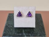une paire de boucles d'oreilles violettes posées sur un bloc de marbre