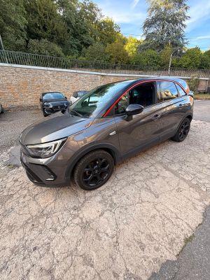 une voiture grise garée sur un parking, à côté d'un mur de briques