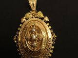 a close up of a gold pendant on a black surface