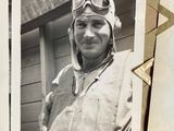 black and white photograph of a man wearing a pilot ' s hat and goggles