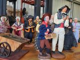 many figurines of people standing around a wheelbarrow