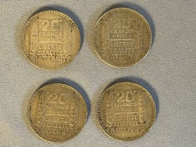 quatre types différents de pièces d'or posées sur un tissu blanc